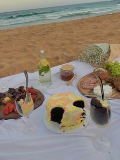 a table with desserts and drinks on it at the beach