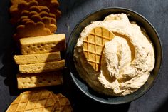 some waffles and crackers in a bowl on a table with cheese dip