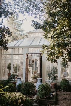 an old greenhouse with potted plants in the foreground and glass doors to the back