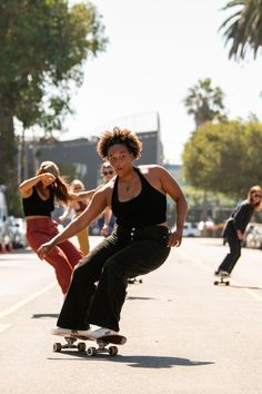 two women skateboarding down the street while others watch