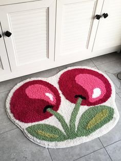 a bathroom rug with two red flowers on it