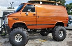 an orange pick up truck parked in front of a fence