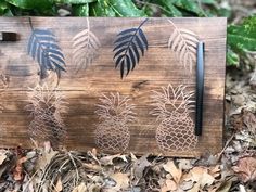 a wooden sign with pineapples on it in the leaves next to some plants