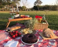 a picnic table with bread, fruit and wine on it in the middle of a field