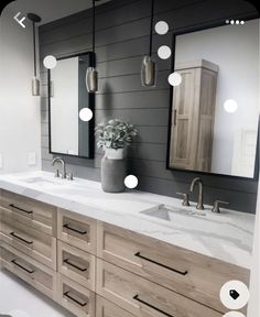 a bathroom with two sinks, mirrors and lights on the wall above them is shown