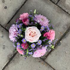 a bouquet of flowers sitting on top of a cement floor next to a brick sidewalk