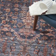 a blue and red rug with a white vase on it next to a wooden chair