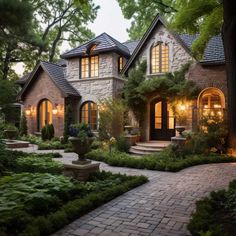 a brick house surrounded by greenery and trees at night with lights on the windows