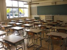 an empty classroom filled with wooden desks and chairs