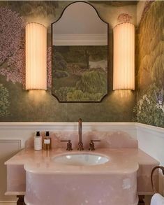 a bathroom sink with a mirror above it and lights on the wall next to it