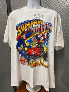 a white t - shirt with an image of a man driving a race car on it