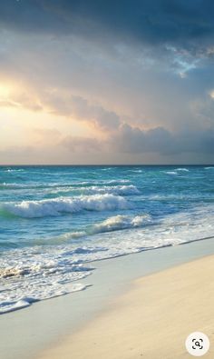 an ocean beach with waves crashing on the sand and clouds in the sky above it