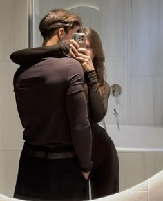 a man and woman taking a selfie in front of a bathroom mirror with their reflection