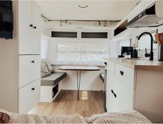 the interior of a camper with white cabinets and wood flooring