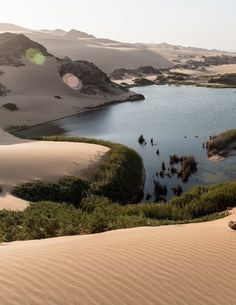 a lake surrounded by sand dunes in the desert