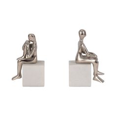 two small silver figurines sitting on blocks