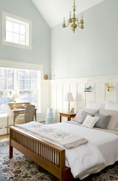 a bed sitting in a bedroom next to a window with two lamps on either side of it