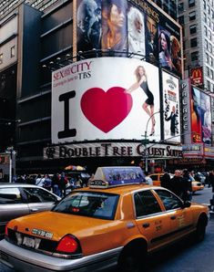 a taxi cab is stopped in front of the new york city times square advertisement for i love ny