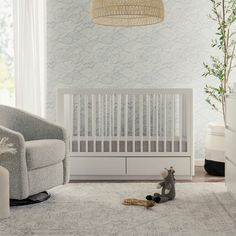 a baby crib with a stuffed animal on the floor next to it and a lamp hanging from the ceiling