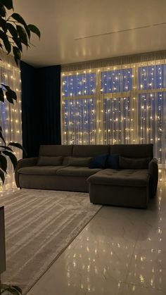 a living room filled with lots of furniture next to a large window covered in lights