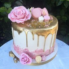 a white and gold cake with pink flowers on top