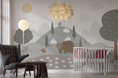 a baby's room with a crib, chair and wall mural