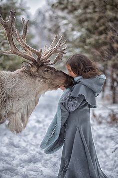 a woman kissing a reindeer in the snow