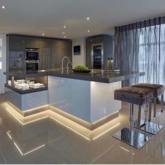 a modern kitchen with an island in the middle and lights on it's sides