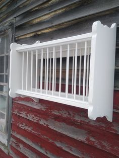 a white window sill on the side of a red wooden building next to a brick wall