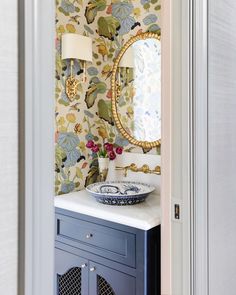 an image of a bathroom with wallpaper on the walls and a mirror above it