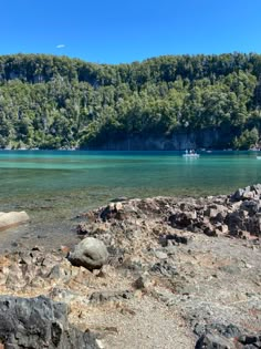 a body of water surrounded by rocks and trees on the side of a mountain range