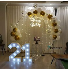 a birthday party with balloons, lights and a cake in the shape of number twenty