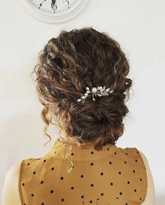 a woman with curly hair wearing a polka dot dress in front of a wall clock