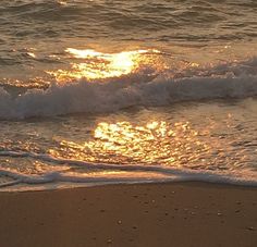 the sun is setting over the water at the beach