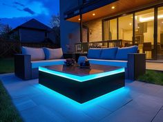 an outdoor living area with couches and tables lit up by blue lights at night