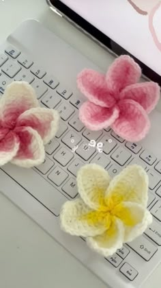 three crocheted flowers sitting on top of a laptop computer's key board