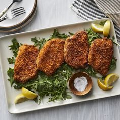 some food on a white plate with lemon wedges