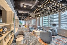 an office lobby with chairs, tables and shelves in front of large windows looking out onto the city