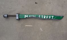 a green street sign laying on the ground next to a broken wrench and screw