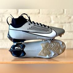 a pair of white and black shoes on top of a wooden table next to a brick wall