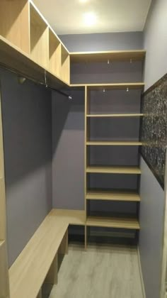 an empty walk - in closet with wooden shelves and shelving