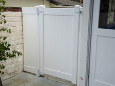 a white gated in area next to a brick building with a potted plant