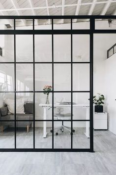 an office with glass walls and white furniture in the background is seen from across the room