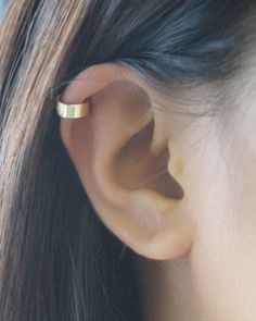 a close up of a person's ear with a small gold ring on it