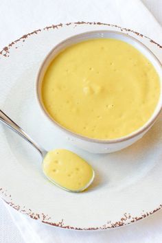 a white plate topped with a bowl of soup next to a spoon