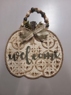 a wooden sign that says welcome hanging on the side of a wall with a bow