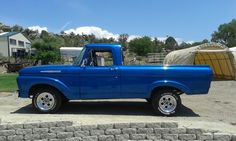 an old blue pickup truck parked in a driveway