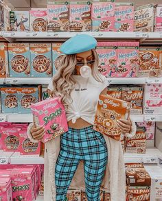 a woman standing in front of boxes of doughnuts and holding a pink box