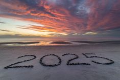 the word 2012 is made out of rocks in the sand at the beach as the sun sets