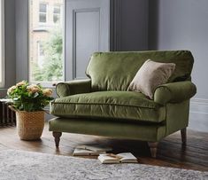 a living room with a green couch and potted plant on the floor next to it